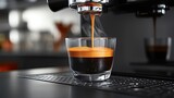 Espresso coffee pouring from an espresso machine in a bar, a closeup shot of a glass cup with a black or brown-colored crema on top of it. Blurred background of a modern cafe interior