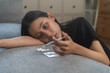 © KMPZZZ - Anti drug, drug addict asian young woman, girl hand holding for syringe, medicament with narcotic on couch at home, abuse overdose. Sick pain of health, unhealthy people. Suicide depressed or despair