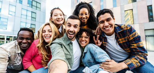 Wall Mural - Multicultural group of young people taking selfie pic with smart mobile phone outside - Happy friends looking at camera together - Youth community concept