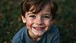 © Tom - Joyful young boy smiling brightly outdoors during a sunny afternoon in a lush green park setting. Generative AI