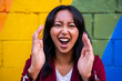 © Westend61 - Cheerful woman screaming in front of multi colored wall