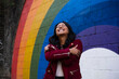 © Westend61 - Happy woman hugging self in front of multi colored wall