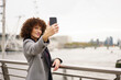 © Westend61 - Smiling woman taking selfie through smart phone near Thames river in London city, England, UK