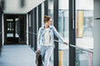 © Westend61 - Businesswoman looking out of window in office passageway