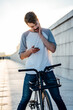 © Westend61 - Young man with commuter fixie bike looking at cell phone