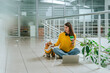 © Westend61 - Smiling businesswoman with pet dog sitting on floor in office lobby