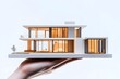 © Agri - A Hand Holding a Modern House Model with Illuminated Windows