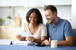 © PheelingsMedia - Happy couple reading bank statement in the kitchen