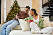 © LIGHTFIELD STUDIOS - A couple relaxes in their cozy apartment, surrounded by Christmas decorations and lights.