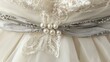 © azi - Close-up of ivory wedding dress detail; pearl and grey ribbon sash.