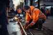© Наталья некрасова - A construction worker wearing a hard hat and reflective vest stands near traffic barriers, overseeing road repairs as team members work in the background