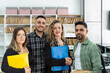 © JoseIMartin - Four business colleagues holding folders and smiling in a modern office with archive files in the background