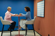 © Seventyfour - Side view of senior and younger female colleagues talking at cafe table developing design of new project while sitting on high chairs in modern coworking space, copy space