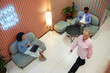 © Seventyfour - Wide angle shot of coworking lounge area where creative team working and video calling on laptops while sitting on comfy seats