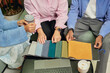© Seventyfour - Cropped shot of diverse group of three interior designers choosing fabric on samples in different colors while working collaboratively at table in coworking lounge area
