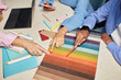 © Seventyfour - Cropped shot of diverse team of designers choosing fabric among various color samples on tabletop while working collaboratively on new project at workplace, copy spac