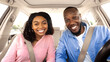 © Prostock-studio - Front portrait of smiling beautiful African American couple sitting in modern luxury car, happy excited young man and woman posing looking at camera, enjoying road trip or buying new car