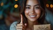© Fotograf - A happy woman holding a present and giving a thumbs up, perfect for celebrating successes or acknowledging good deeds