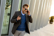 © BGStock72 - Businessman engaged in a phone conversation during a sunset stroll near modern architecture