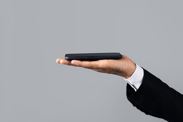 Poster - Unrecognizable businessman in formal attire holds a smartphone in his palm, closeup, cropped