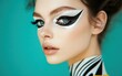 © Marina - A close-up of a woman with graphic eyeliner in white and black with glossy highlighter on her cheekbones on a rich teal background