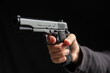 © Rawf8 - Hand holding a gun closeup, armed man on dark background. Danger and crime