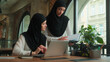 © Yuliia - Muslim businesswomen Islamic girls business ladies women in hijab discuss laptop project corporate education female mentor leader teach advice help intern with computer online work studying in office