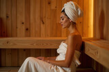Happy woman in a sauna in a spa salon. A woman relaxes in a steam bath, dressed in a towel. Portrait of a woman in a spa.