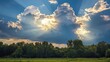 © hazia - Sunbeams bursting through dramatic clouds above a lush green field and forest.