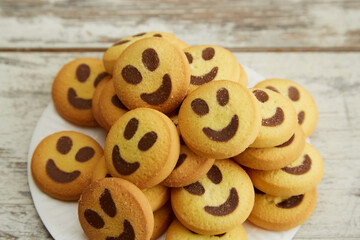 A stack of yellow cookies shaped like smiling emojis on a plate in close-up, a big company, good mood, festive atmosphere, family coziness.