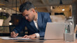 © Yuliia - Indian businessman male ethnic entrepreneur leader corporate manager agent work computer laptop paperwork on desk Arabian guy business man guy employer worker looking pc screen project in office cafe