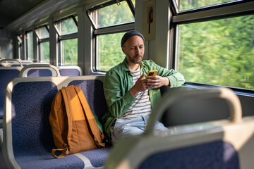 focused man leans into smartphone, scrolling social media and chatting, checking train schedule on c