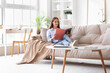 © Pixel-Shot - Beautiful young happy woman reading magazine on sofa at home