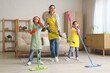 © Pixel-Shot - Mother and her children in headphones having fun while cleaning at home