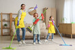 © Pixel-Shot - Mother and her children in headphones having fun while cleaning at home