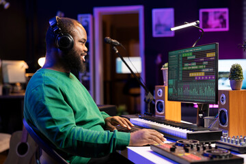 Fototapete - Music producer editing old audio recordings on professional software, operating on mixing console and stereo gear. Sound engineer producing new songs with acoustical tunes in home studio.