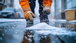 © Prasanth - A city worker wearing gloves spreads salt on a slippery, icy sidewalk during winter, helping prevent accidents and ensuring pedestrian safety in snowy conditions.