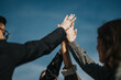 © qunica.com - A dynamic image of business people coming together and celebrating success with a high five under the clear blue sky, symbolizing teamwork and unity.