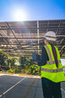 © ultramansk - Engineer in safety vest and helmet pointing towards a solar powered carport, illustrating eco-friendly innovation in parking infrastructure. Solar panels provide shade and sustainable energy.
