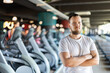 © JackF - Young guy trainer in sportswear poses in middle of fitness center gym. Active lifestyle, daily workouts in crossfit gym