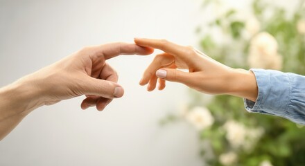 Two hands reaching towards each other against soft, blurred background