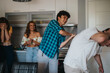 © qunica.com - Group of friends enjoying laughter and fun in a modern kitchen setting. The scene captures joy, humor, and friendship in a casual home environment.
