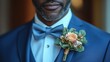 © Centric  - Close up of a groom wearing a blue suit with a boutonniere, showcasing his elegant attire for a special occasion
