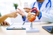 © M+Isolation+Photo - A woman with heart disease visits a doctor at the table in a hospital. The doctor explains conditions like coronary artery disease, arrhythmia,and heart valve disease,providing advice and medication