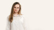 © golubovy - Serious teenager portrait. Lady offended. Strict disappointed girl in white posing isolated on light copy space background.