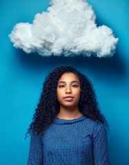 Wall Mural - Young beautiful woman with black curly hair standing against blue background with large fluffy white cloudy floating above her