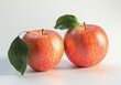 © Maftuh - Two Ripe Red Apples with Green Leaves on a White Background A Still Life Photography of Fresh Fruit