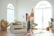 © tonefotografia - Two young  Asian woman friends practicing yoga at home.