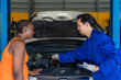 © Verin - mechanic explaining a car problem to africa woman client during examination,concept for business garage service,auto service
