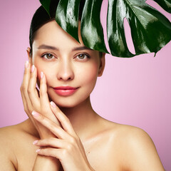 Close up woman face with green exotic leaf. Skin care beauty treatments concept. Model with clean, health skin of face